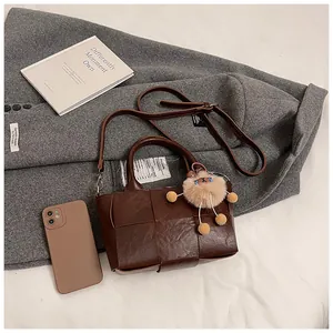 Détail du sac seau tressé avec breloque mouton en peluche et bandoulière réglable