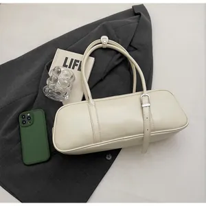Close-up of minimalist cream-white leather baguette bag with silver buckles on a blazer