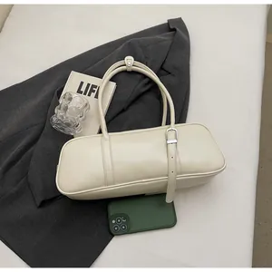 Close-up of cream PU leather baguette bag with silver buckle on a stylish suit background