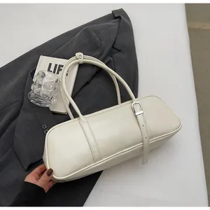 Detail of minimalist cream baguette bag with adjustable strap on professional backdrop