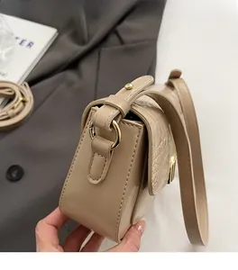 Detail view of gold metal hardware and crocodile texture on beige shoulder bag