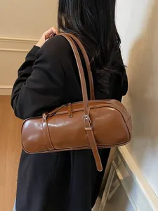 Minimalist deep brown cylindrical baguette bag in glossy leather for women on shoulder