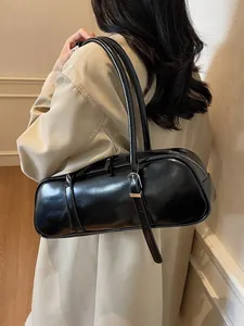 Minimalist black cylinder baguette bag in glossy leather with silver buckles on shoulder straps