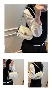 Close-up of white crocodile pattern shoulder bag featuring metal lock and horse charm