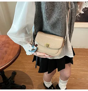 Detail of cream faux crocodile texture saddle bag with gold buckle and horse charm