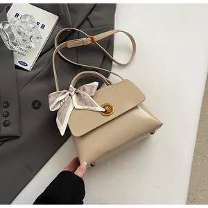 Detail of khaki leather messenger tote with gold twist lock and elegant floral scarf accent