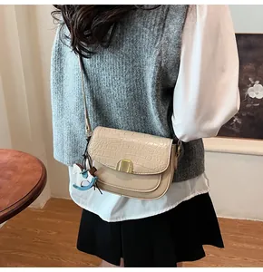 Beige crocodile embossed saddle bag with gold buckle and blue horse charm on model