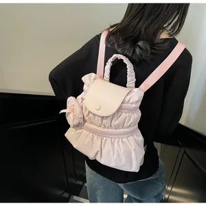 Détail du sac à dos rose à volants avec texture plissée et breloque noeud décoratif