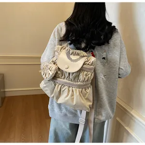 Détail d'un sac à dos plissé beige avec charme en cœur et sangles réglables