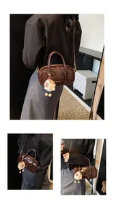 Deep brown leather Boston bag with plush white charm and stylish metal handle detail