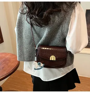 Detail of dark red crocodile embossed saddle bag with gold buckle and horse charm