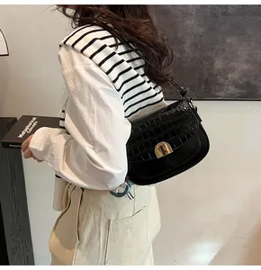 Detail of crocodile pattern saddle bag with golden arch buckle and adjustable strap