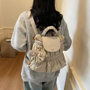 Sac à dos plissé crème chic avec breloque cœur porté par un mannequin féminin
