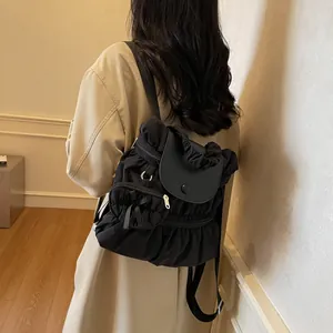 Sac à dos noir plissé chic avec rabat porté par un mannequin dans un intérieur chaleureux