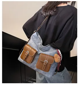 Detail view of large grey-blue canvas tote with brown leather pockets and teddy bear charm