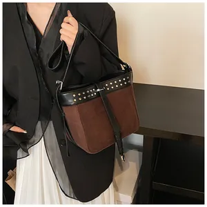 Detail of color-block bucket bag with silver rivets and adjustable black strap worn by model