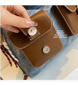 Detail of strong magnetic buckle on blue denim tote bag with brown leather pocket