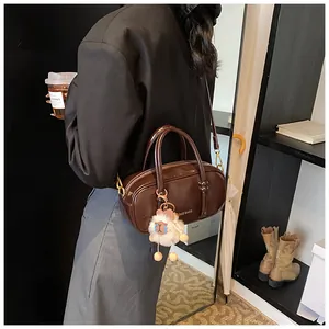 Detail view of dark brown patent leather boston bag with fluffy sheep pendant accessory