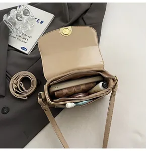 Internal view of beige crocodile pattern saddle bag showing main storage and zip pocket