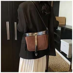 Detailed view of a vintage dark brown suede messenger bag with rivets and leather strap