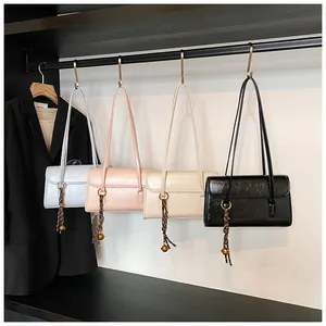 Detail view of four pleated PU leather underarm bags with metal ring and tassel charms
