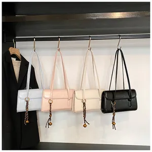 Detail of four fashionable underarm bags in blue, pink, beige, and black on a rack
