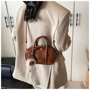 Back view of a glossy dark brown crossbody bag on model with cute bear charm