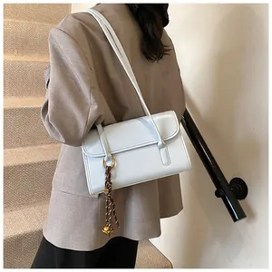 Close-up of light blue leather underarm bag with gold ring and braided rope detail