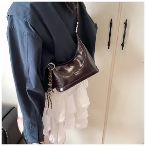 Close-up of a dark brown glossy patent leather hobo bag worn on the shoulder
