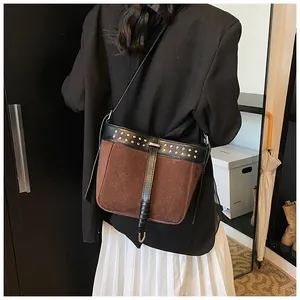 Detail view of vintage suede messenger bag with contrast leather trim and metal rivets