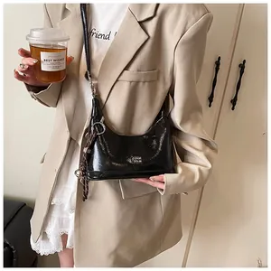 Glossy black hobo bag with silver ring detail and brown charm shown in lifestyle setting
