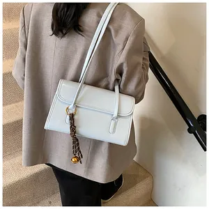 Detailed view of light blue leather shoulder bag featuring plaid tassel and gold bell charm