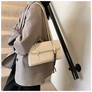 Chic off-white large capacity underarm bag shown worn with a grey blazer on stairs