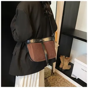 Detail view of two-tone messenger bag with silver rivets and leather strap on model