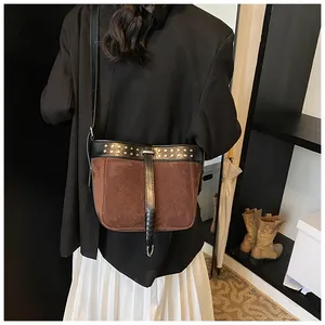 Retro brown suede messenger bag with metal rivets and strap details on a female model