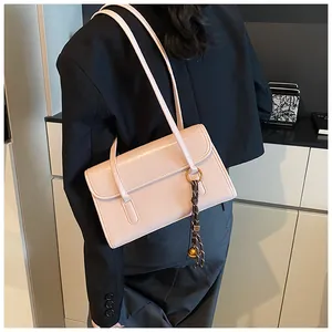 Detail of light pink rectangular shoulder bag with tassel charm and sleek flap closure