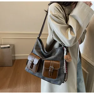 Detail of large canvas tote bag with brown leather pockets on a model wearing a trench coat