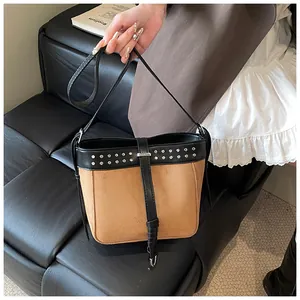 Detail of vintage brown suede bucket bag with silver metal studs and black leather strap