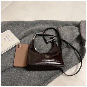 Detail of a deep coffee leather crescent bag with silver metallic logo and sleek strap
