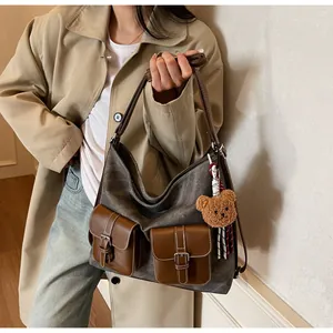 Detail of vintage canvas tote with brown leather trim and cute plush bear charm