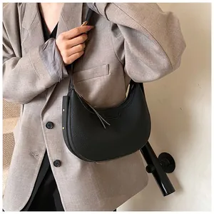 Dettaglio della borsa hobo a mezzaluna nera con trama litchi e logo dorato