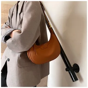 Borsa a mezzaluna in pelle martellata caramello indossata con un blazer grigio per un look urbano