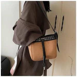 Detail of vintage messenger bag with brown suede finish and silver rivet hardware trim