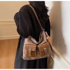 Detail of tan suede tote bag featuring dual brown leather flap pockets and a cute bear charm