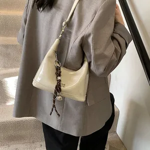 Minimalist beige glossy hobo bag with silver logo and decorative rope charm