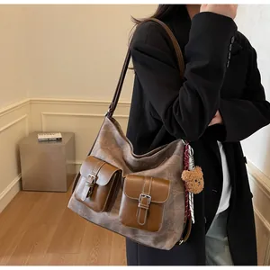 Detail of vintage brown tote bag with flap pockets and plush bear charm on model