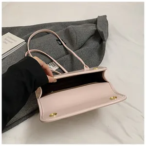 Detail of pink faux leather shoulder bag showing magnetic closure and interior compartments