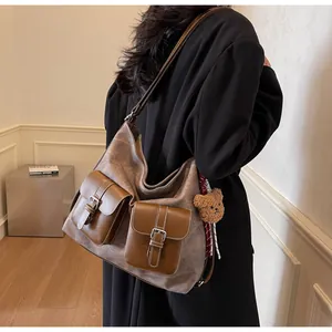 Detail of vintage tote bag with dual front pockets and brown plush bear charm