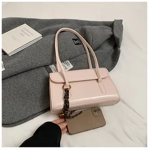 Light pink shoulder bag with woven strap detail and smartphone for size scale