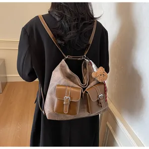 Detail of vintage caramel brown tote bag with pockets and plush bear charm on model